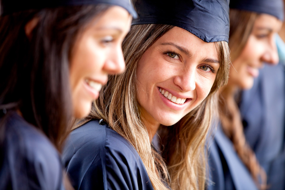 Beautiful female graduate standing out from a group of students